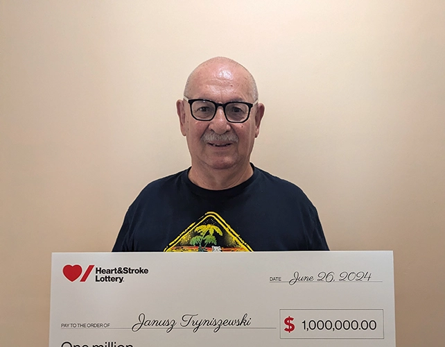 Janusz Tryniszewski holds a cheque from Heart & Stroke Lottery for $1 million
