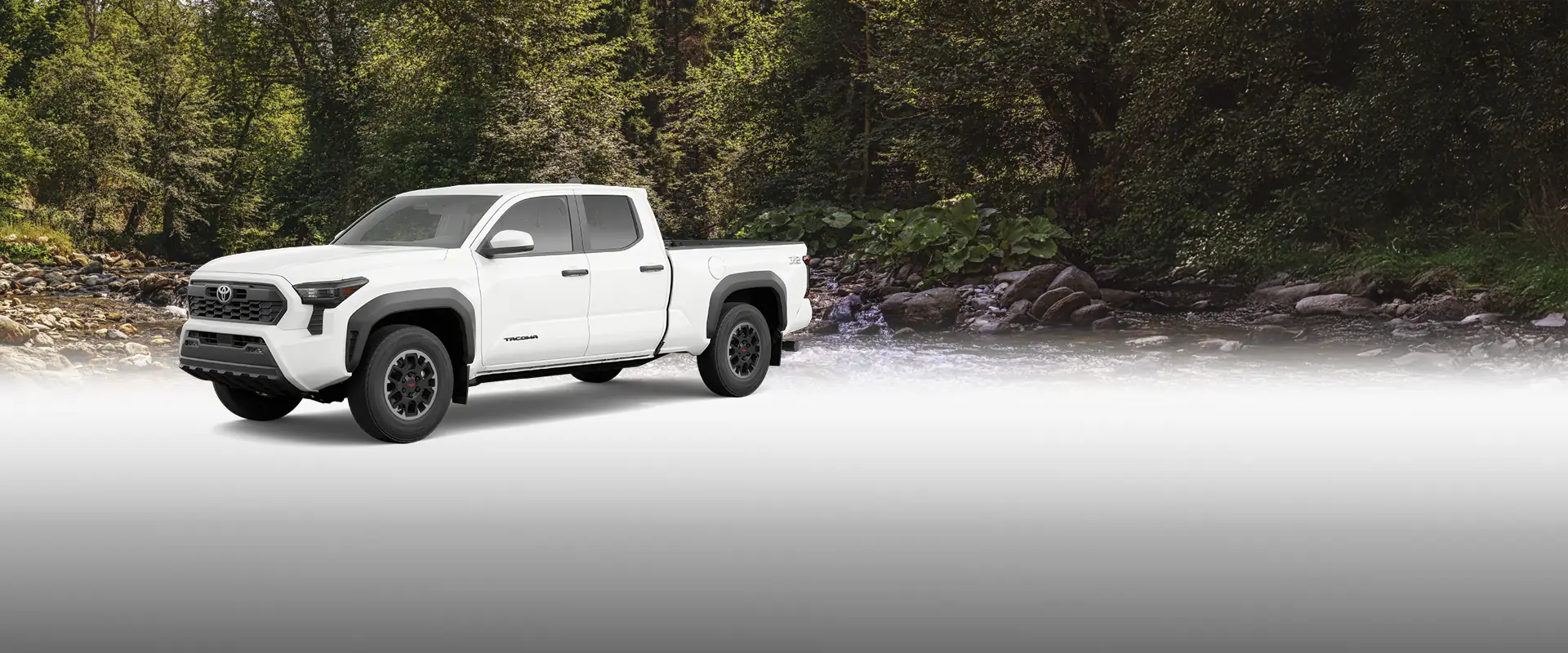 A Toyota Tacoma truck parked in front of a picturesque countryside backdrop.