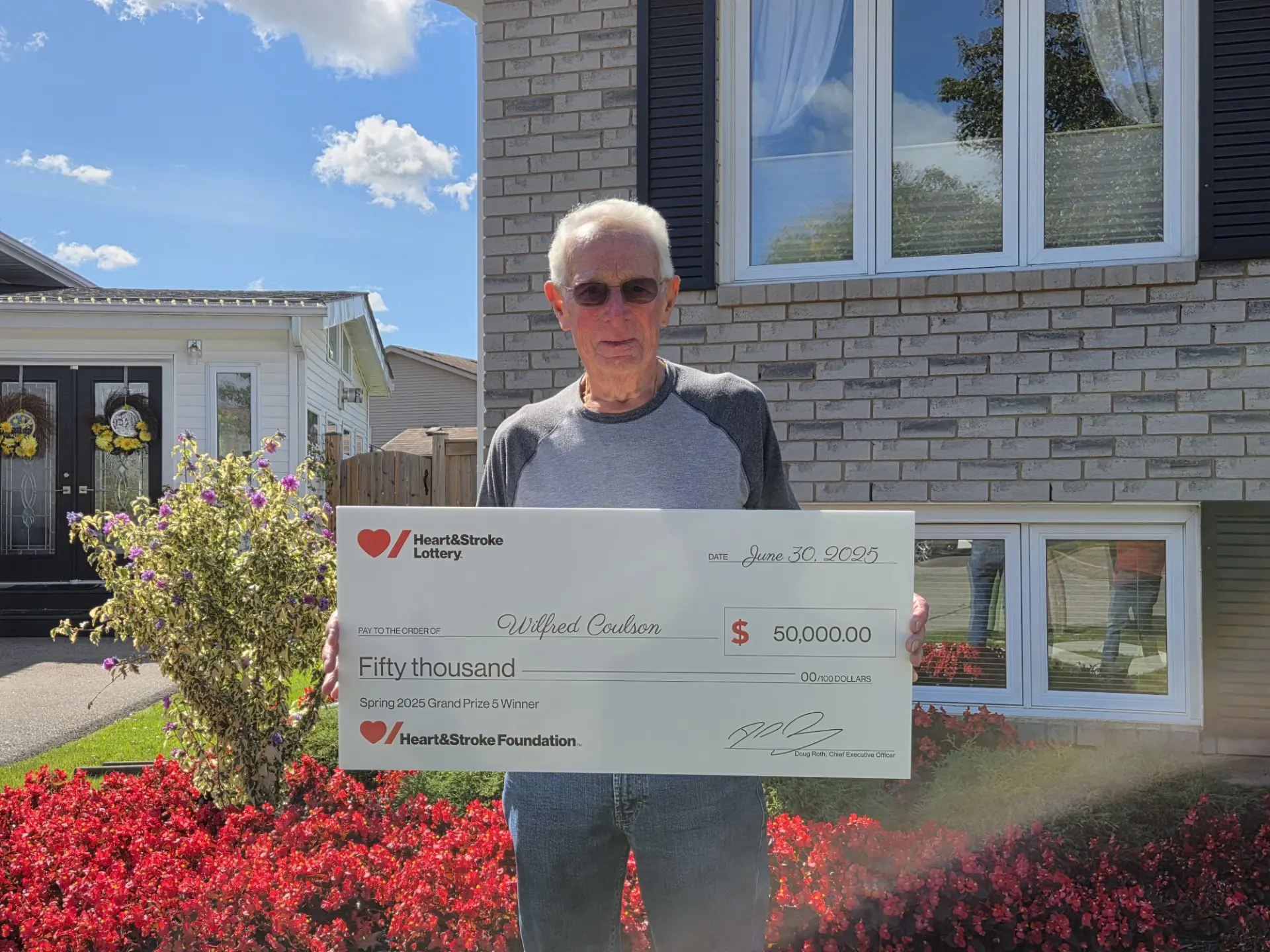 Spring 2025 Lottery – Grand Prize 5 Winner Wilf Coulson holding a novelty cheque for his winning. 