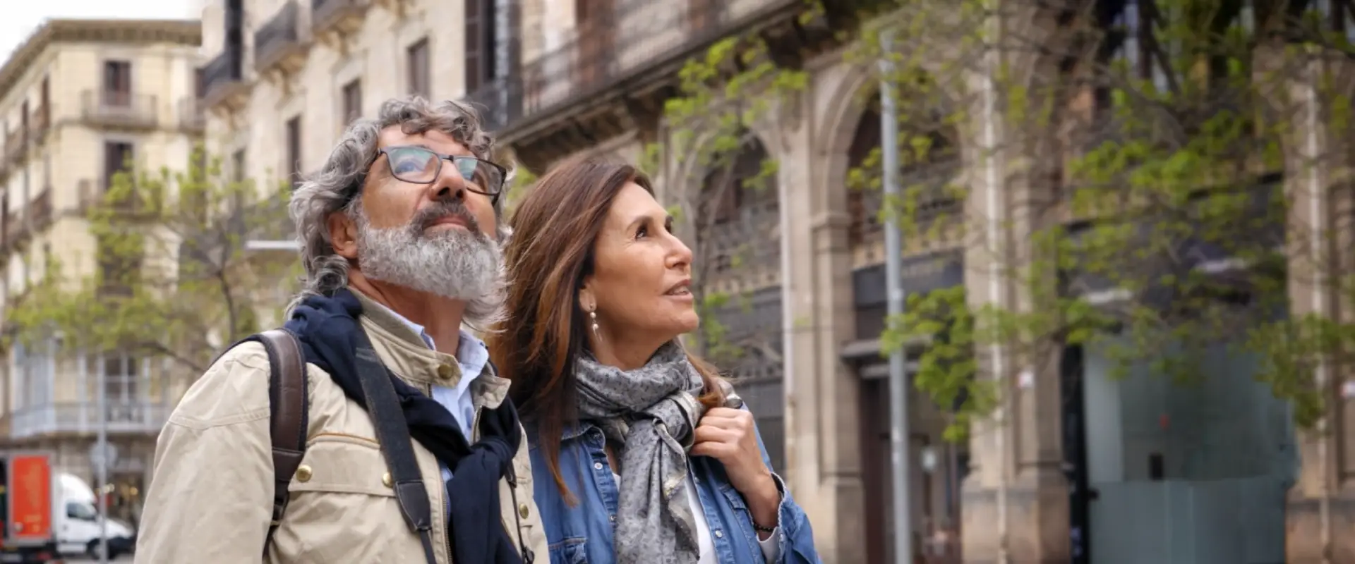 A happy senior couple smiles as they explore a beautiful European city.
