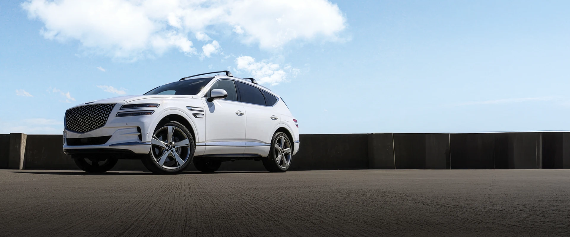A white Genesis GV80 in a rural landscape. 