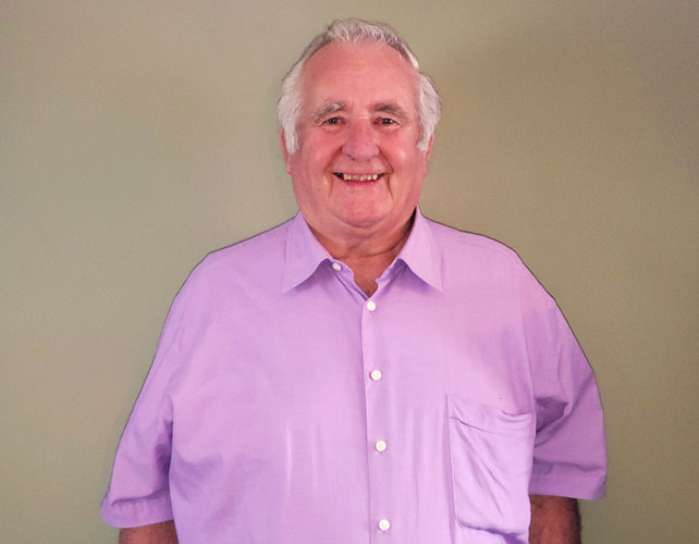 Elderly man standing against brown background