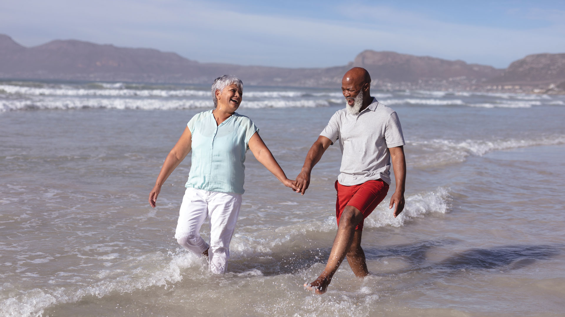 Happy senior african american couple holding hands and having fun on the beach