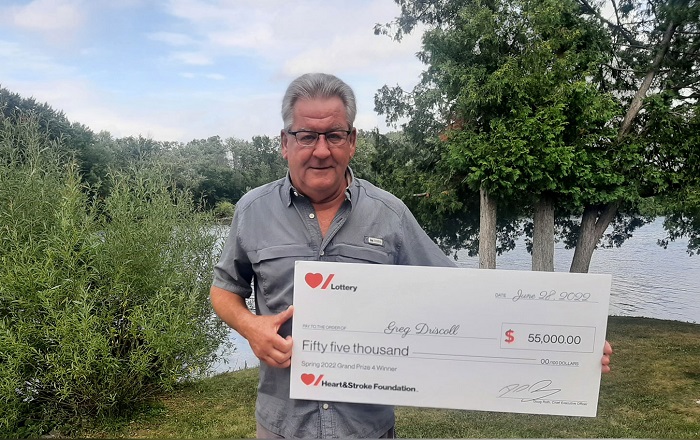 Heart & Stroke Spring 2022 Lottery Grand Prize #4 winner Greg Driscoll holding his cheque for $55,000