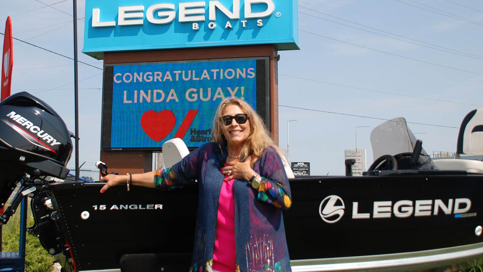 Woman standing in front of fishing boat and large Legend Boat business sign 