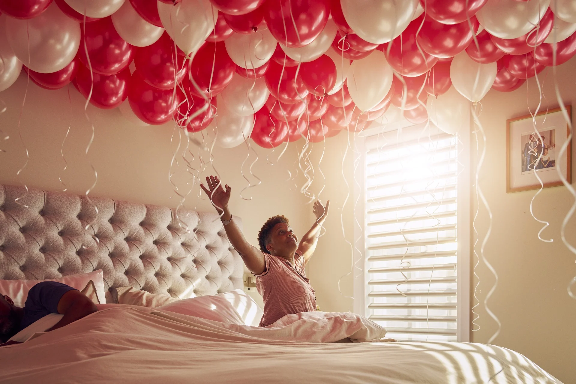 Katherine celebrates in bed with a room full of balloons