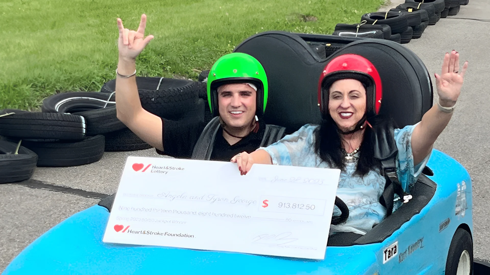 50/50 Lottery winners Tyson and Angela George hold a cheque for $913,812.50 while riding in a go-kart