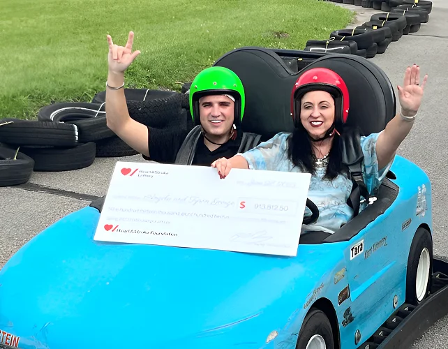 50/50 Lottery winners Tyson and Angela George hold a cheque for $913,812.50 while riding in a go-kart