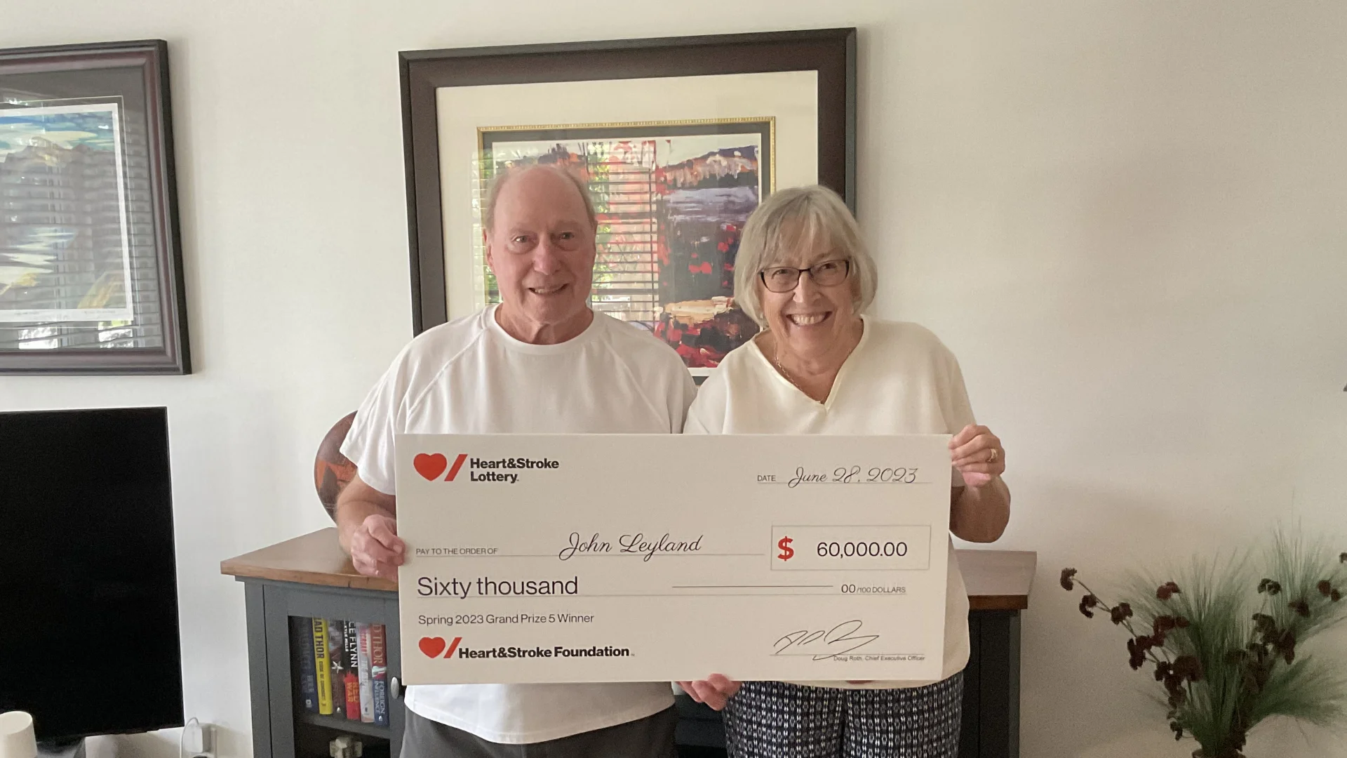 John Leland and his wife hold a cheque for $60,000