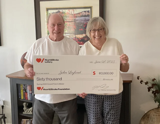 John Leland and his wife hold a cheque for $60,000