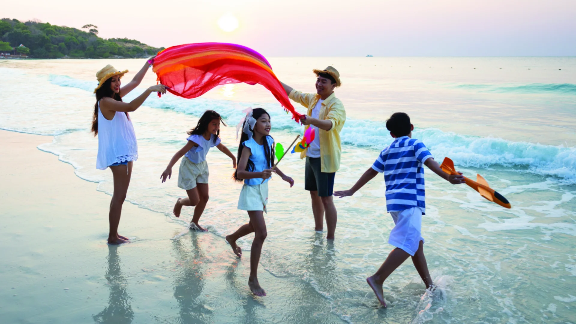 A family of five plays on a beach.