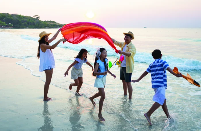 A family of five plays on a beach.