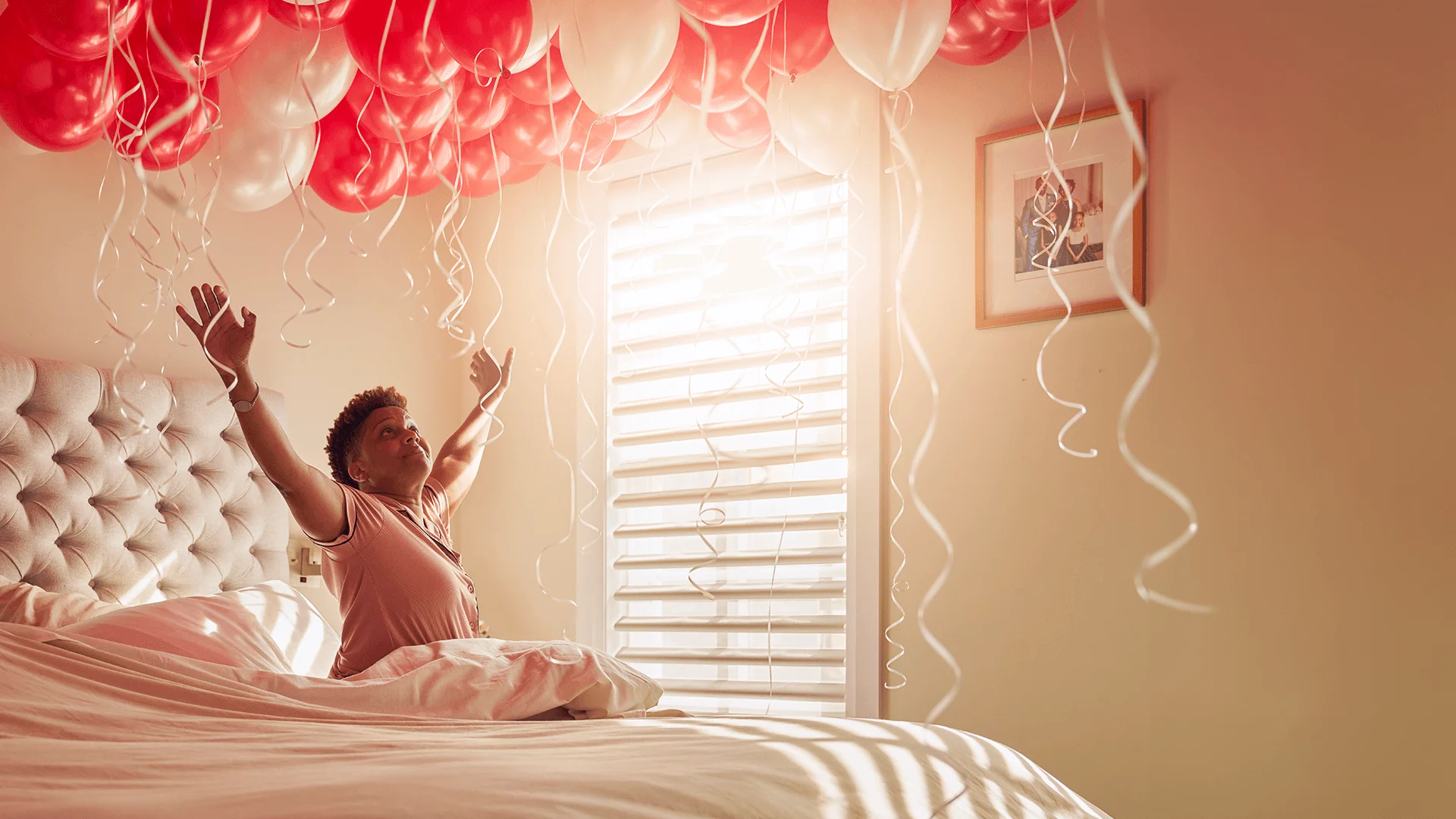 Katherine celebrates in bed with a room full of balloons