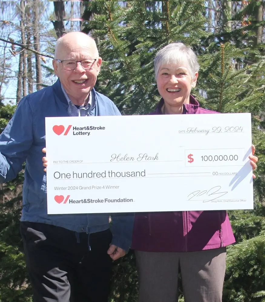 Helen Stark and her husband hold a giant cheque for $100,000