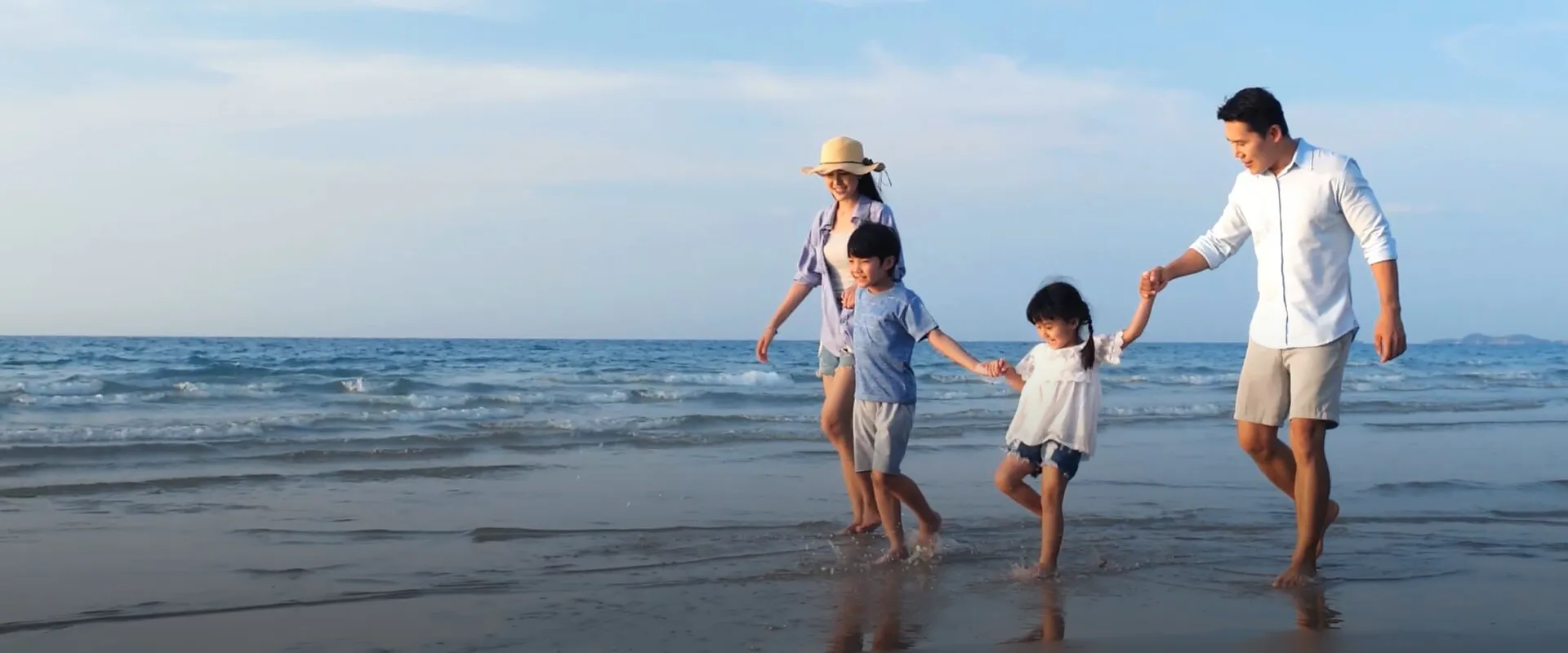 四口之家愉快地在海灘上散步 