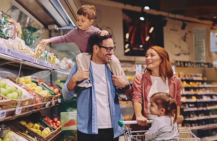 A family of 4 shopping in a grocery store happily.