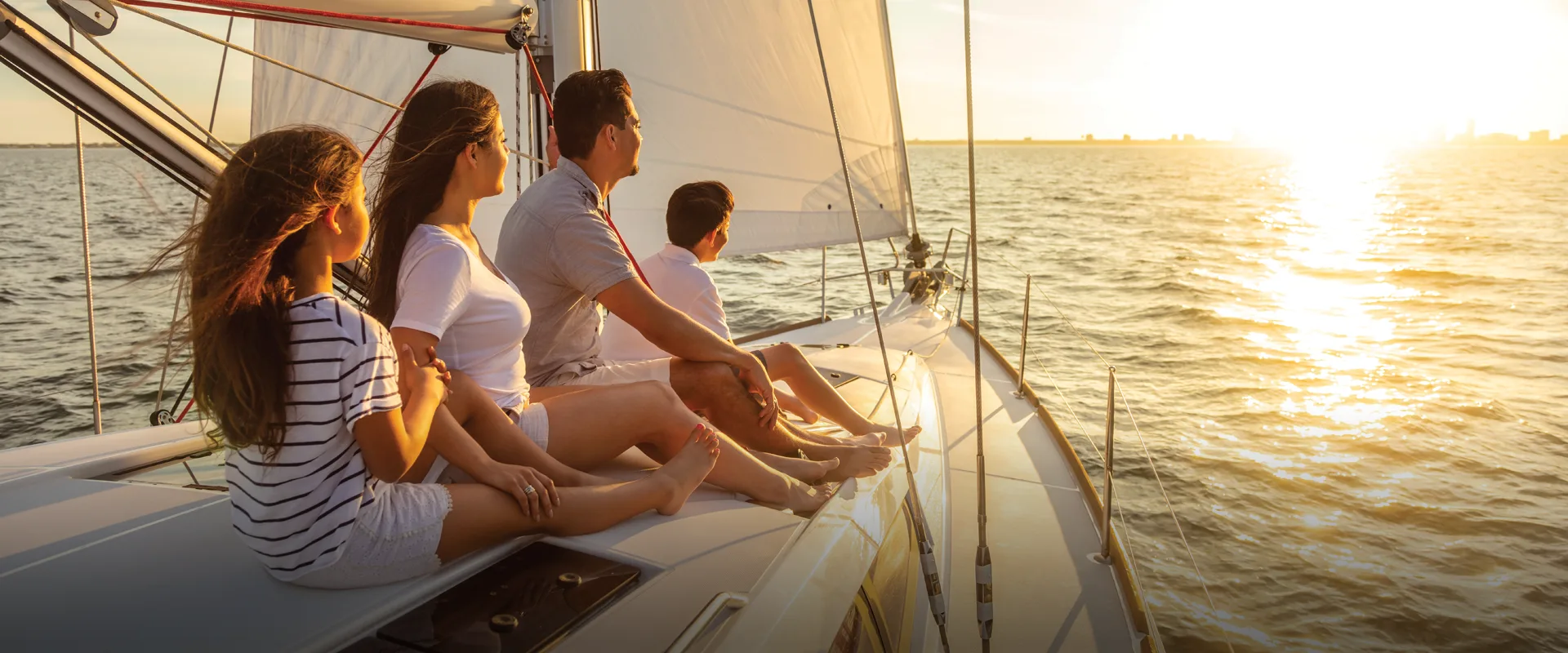 A family with children sailing on a luxury boat, enjoying the view of the sunset.