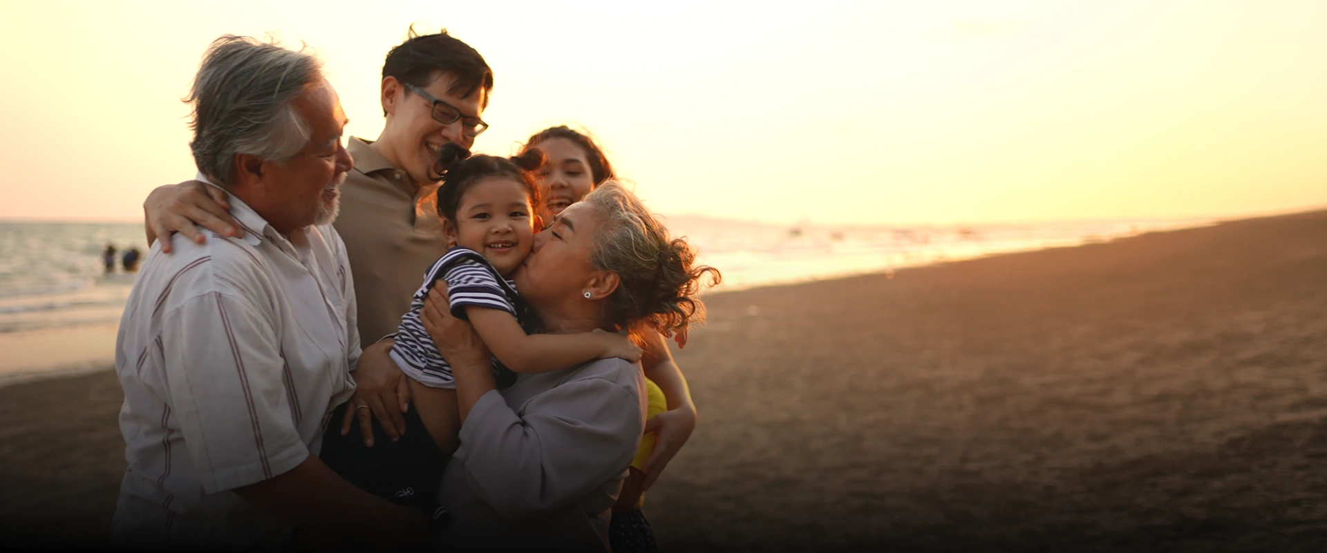 A joyful multi-generation family together on a beach.