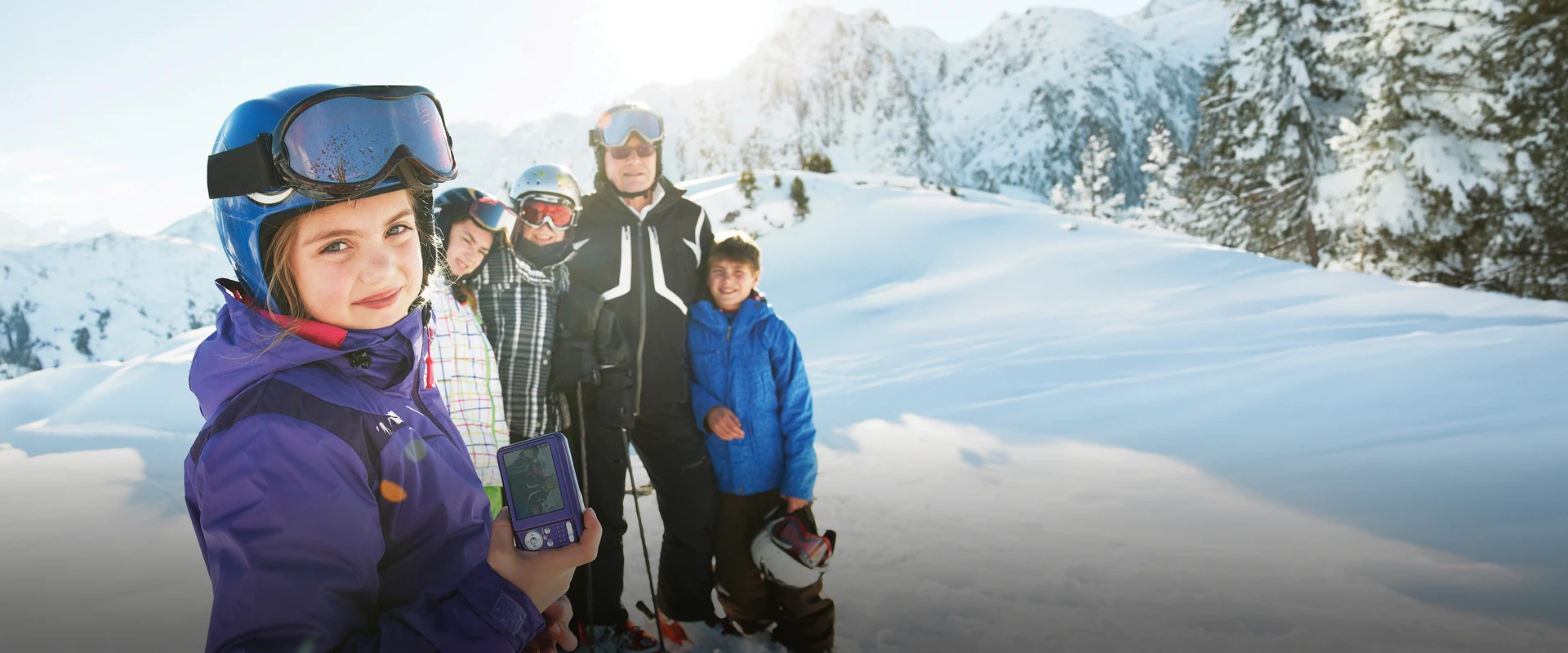 A family of four with ski equipment posing on a snowy mountain during a ski trip.