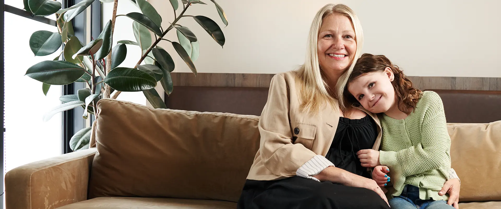 Natalie sitting on the couch snuggling with her mom.