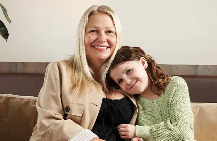 Natalie sitting on the couch snuggling with her mom.