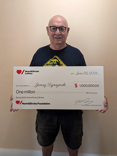 Janusz Tryniszewski holds a cheque from Heart & Stroke Lottery for $1 million