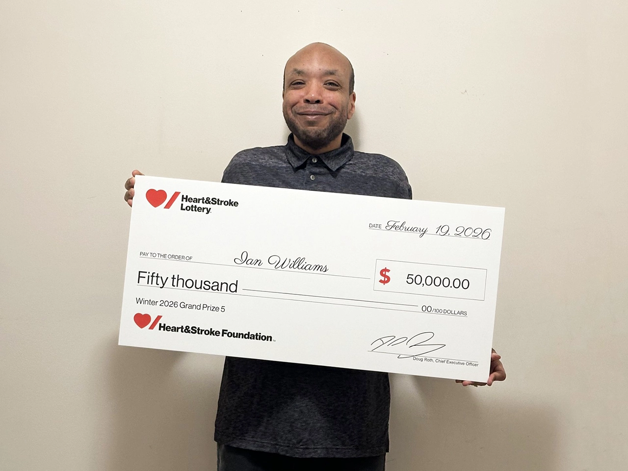 Ian Williams holding a giant cheque from Heart & Stroke Lottery for $50,000
